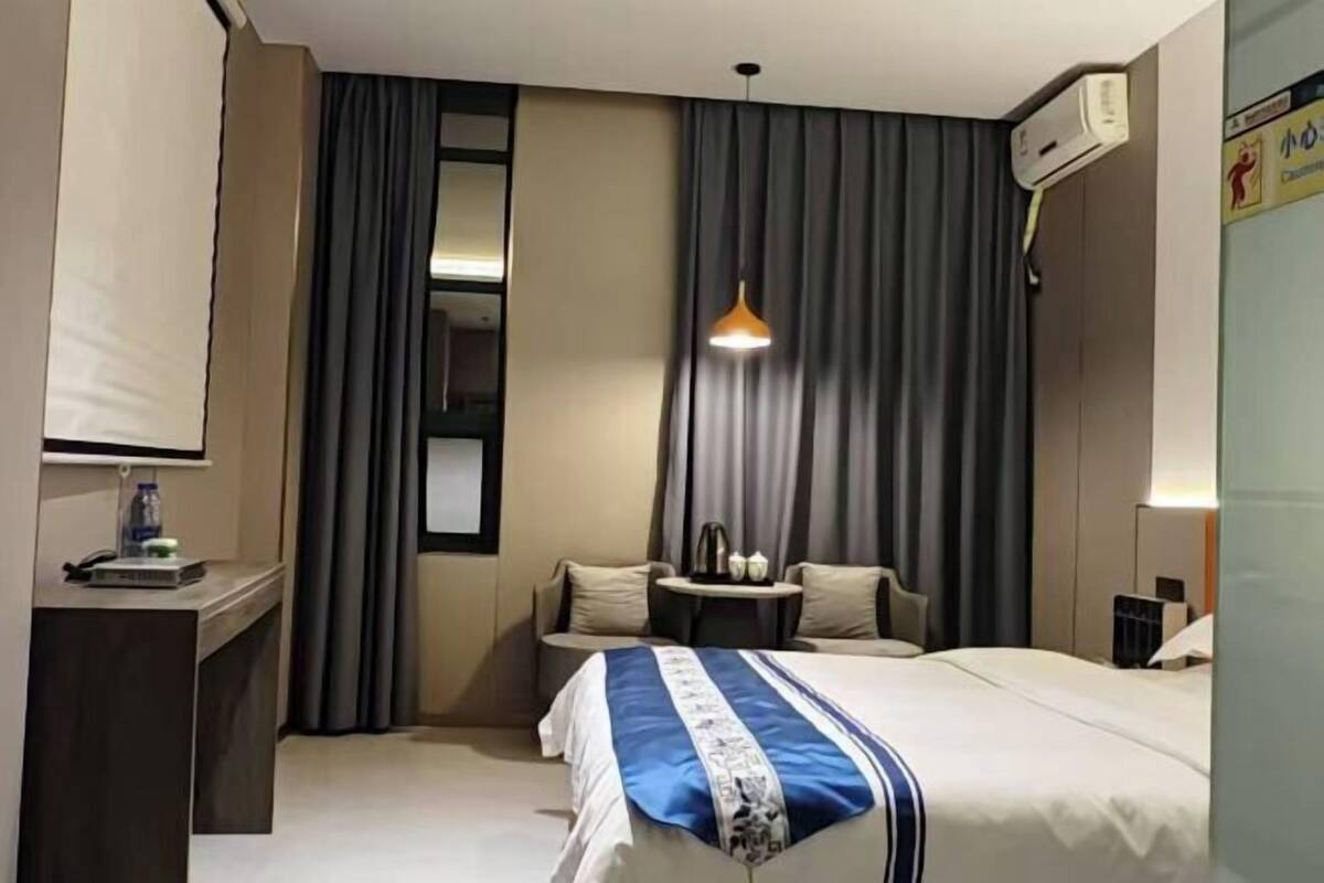 Une chambre d’hôtel comprenant un lit, un bureau, une chaise, une petite table et une lampe.