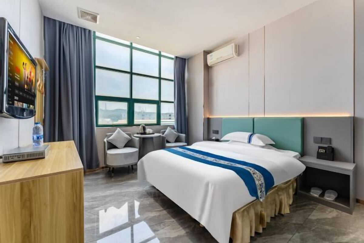 Une chambre d’hôtel avec un lit, un bureau, une télévision, une fenêtre et une vue sur la ville.