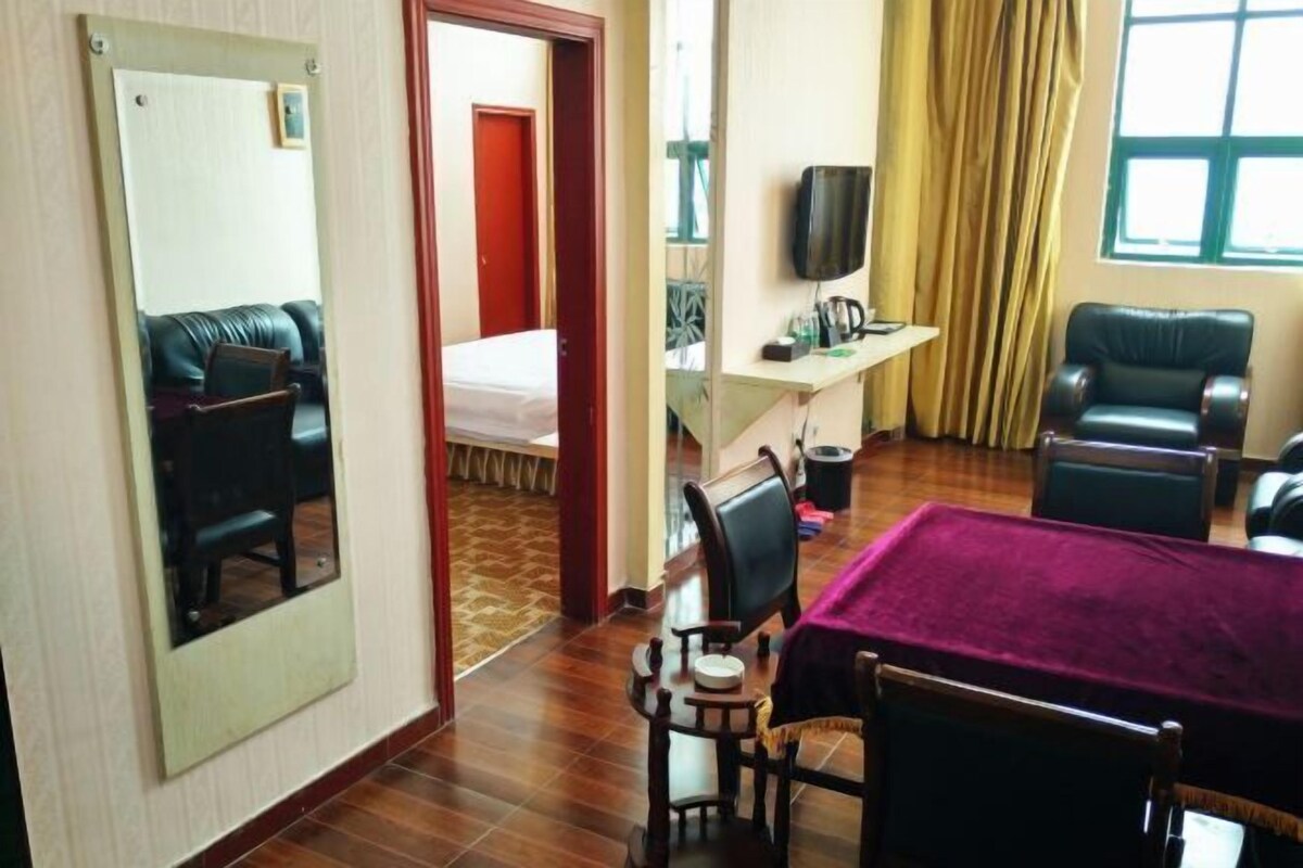 Ein Hotelzimmer mit Bett, Schreibtisch mit Fernseher, Esstisch und Spiegel.