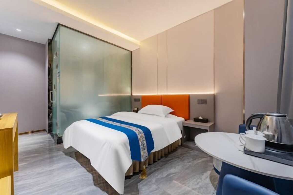 Ein modernes Hotelzimmer mit einem Bett, einem Nachttisch und einem kleinen Tisch mit einem Wasserkocher.
