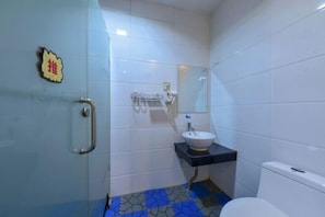 A bathroom with white tiled walls, a black sink, and a white toilet. - Yali Siji Business Hostel (Shenzhen)