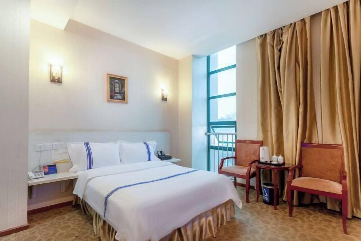 Une chambre d’hôtel comprenant un lit, une table de chevet, une lampe, une chaise et une vue sur l’extérieur.