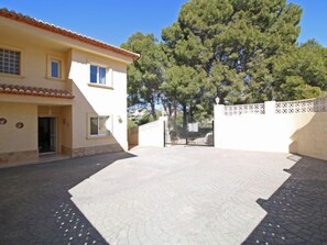 A two-story building with a tiled roof, a paved courtyard, and a gate. - Bajamar by Interhome (Calpe/Calp)