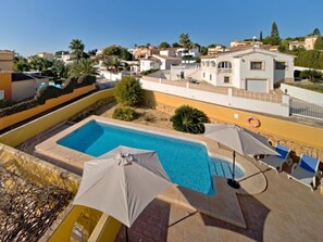 A swimming pool with a clear blue water, surrounded by a yellow wall and a white building with a balcony. - Villa Acuario by Interhome (Calpe/Calp)
