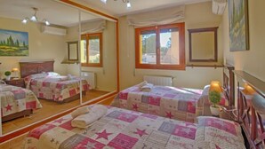 A bedroom with two beds, a large mirror, and a window.