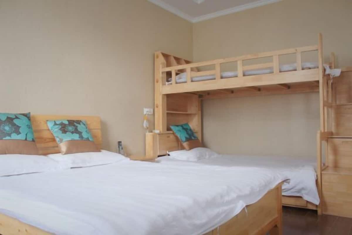 Quarto com duas camas beliche de madeira, cada uma com almofada e mesa de cabeceira.