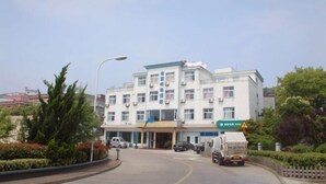 A multi-story building with a central entrance, surrounded by greenery and parked vehicles. - Shengsi Haiwang Mingzhu Homestay (Shengsi)