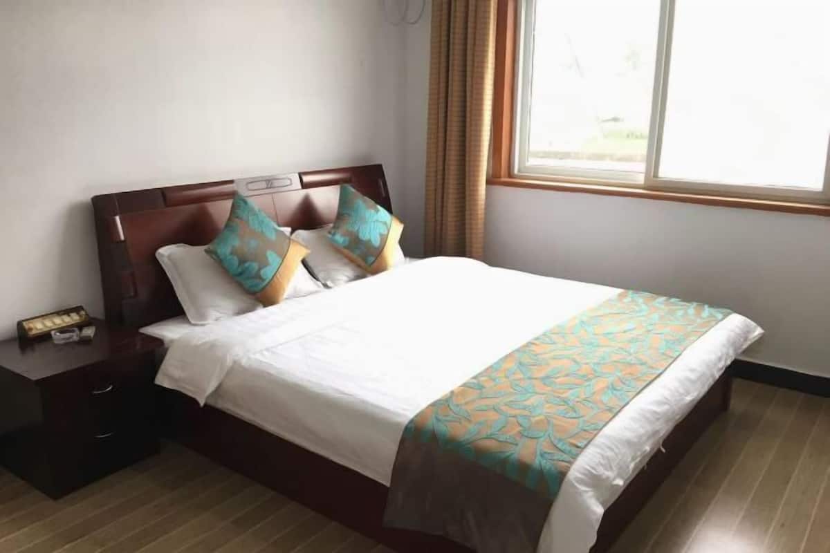Uma cama bem arrumada com colcha estampada, cabeceira de madeira e mesa de cabeceira com abajur.