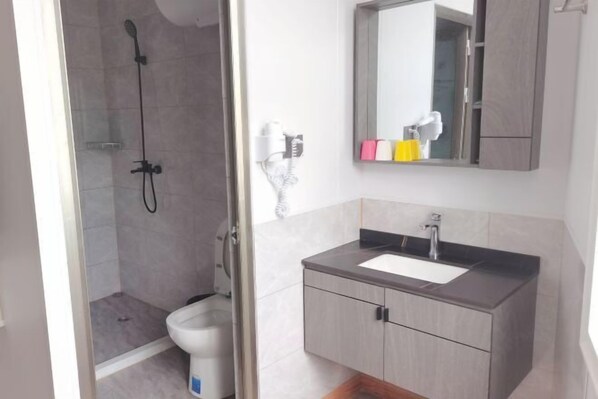A bathroom with a shower, toilet, and a vanity with a sink and mirror.