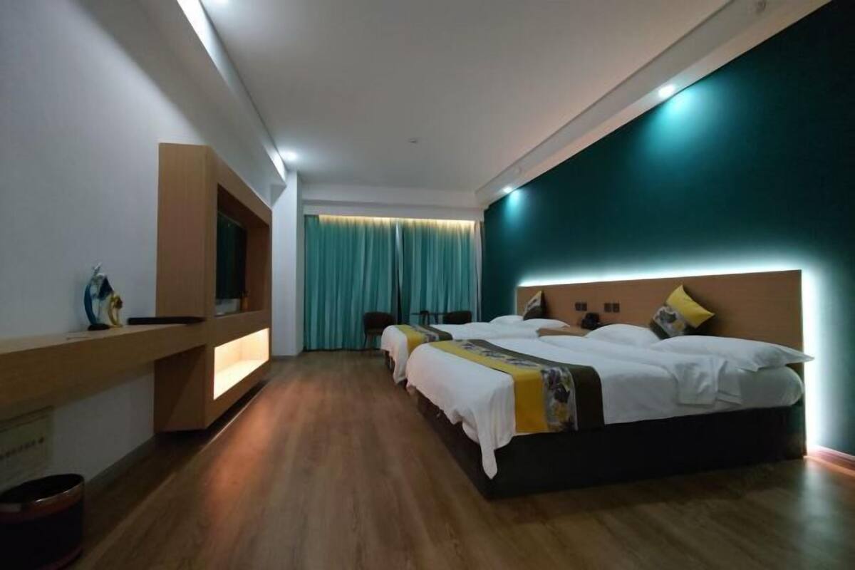 Une chambre d’hôtel moderne avec un grand lit, un téléviseur fixé au mur et un plancher en bois.