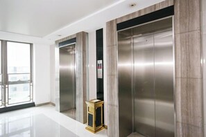 A modern elevator with metallic finish and a small control panel. - Central Business Apartment Hotel (Kunshan)