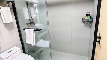 Une cabine de douche fermée par des parois en verre, avec des toilettes blanches et un porte-serviettes.