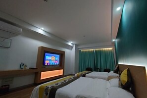 Une chambre d’hôtel avec deux lits, un téléviseur fixé au mur et une fenêtre avec des rideaux.