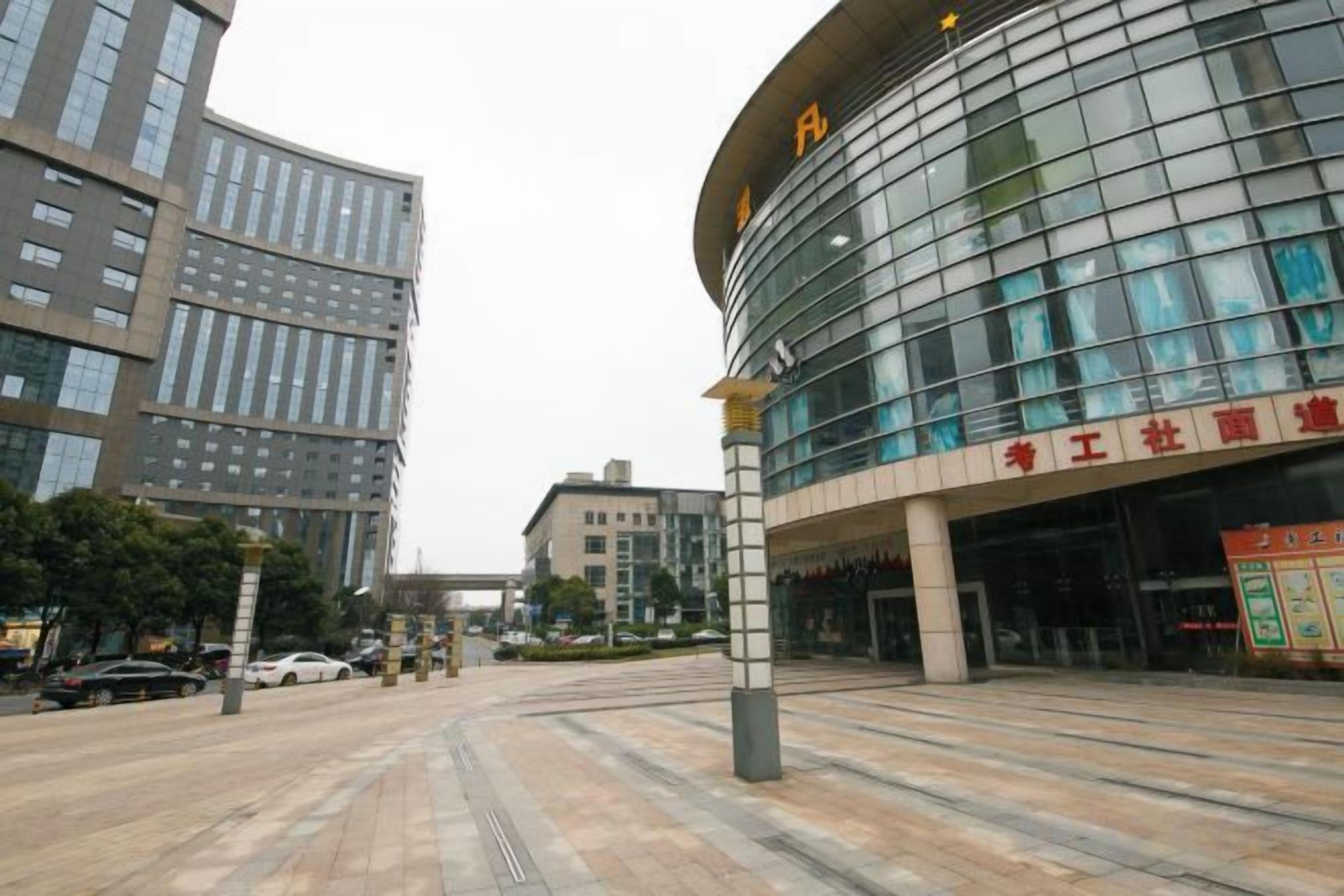 A modern building with a curved glass facade and a sign with Chinese characters.