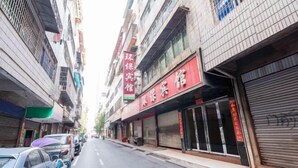 A street view with closed shops, a parked car, and a building with a red sign. - Hengyang Environmental Protection Hotel (Hengyang)