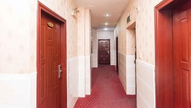 A narrow hallway with red doors, beige walls, and a red carpet. - Hengyang Environmental Protection Hotel (Hengyang)