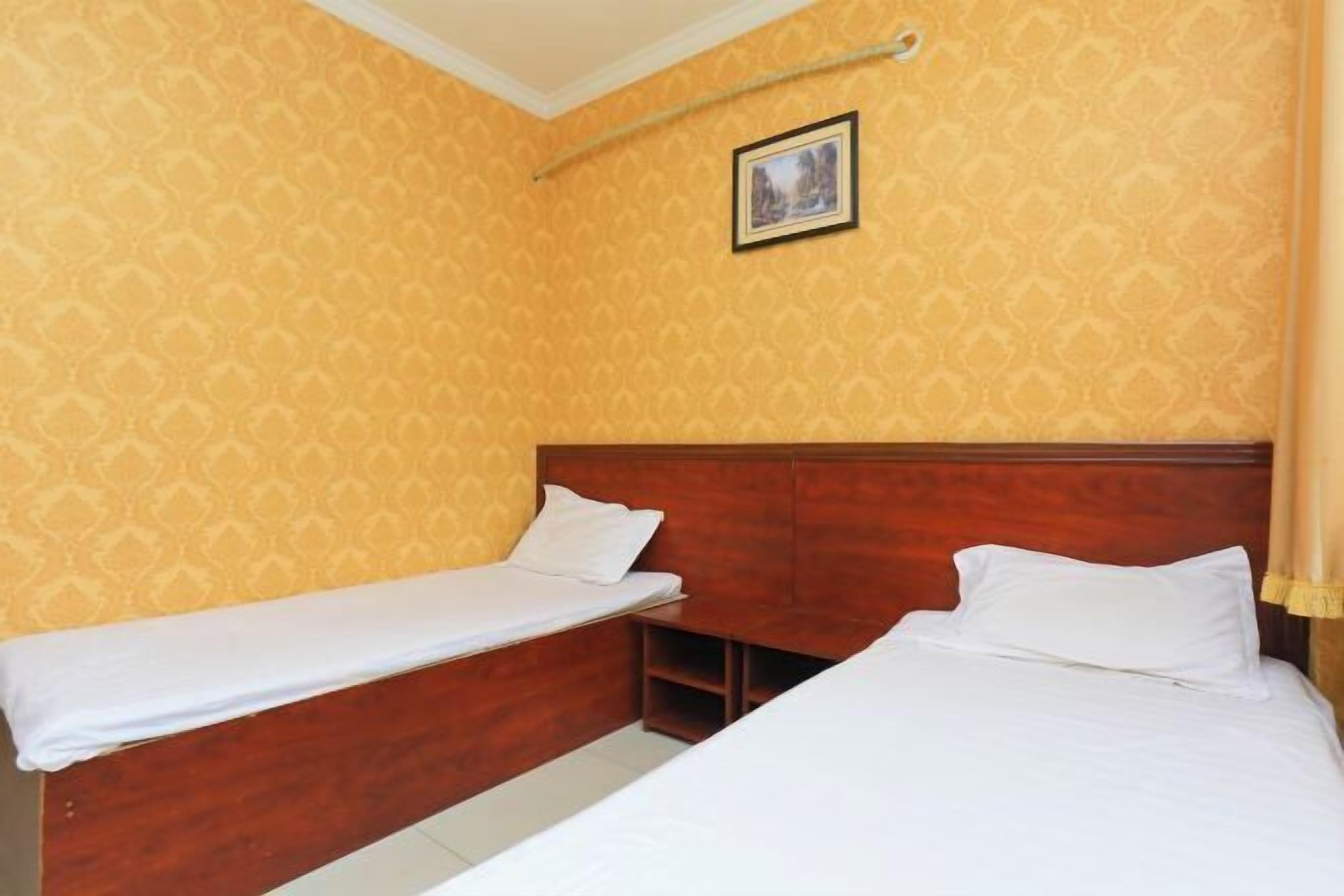 Une chambre avec deux lits, des têtes de lit en bois et un papier peint à motifs.