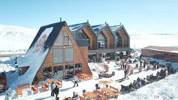 A modern ski resort with wooden cabins and a communal outdoor area with benches and tables.