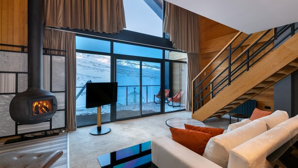 Una sala de estar moderna con chimenea, ventanas amplias, un sofá y una escalera.