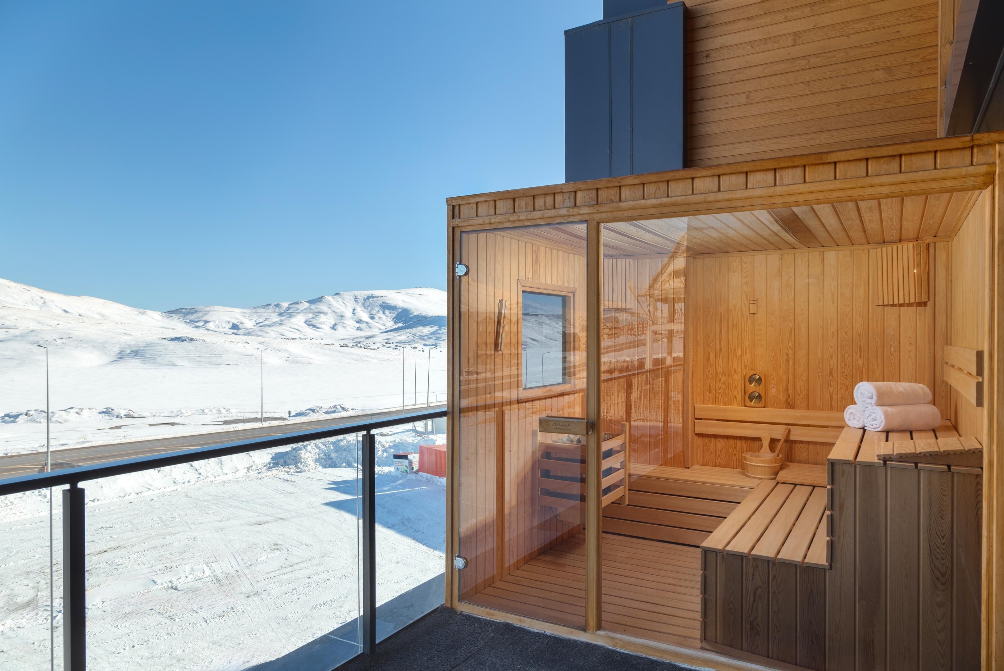 A wooden sauna with a glass door, a bench, and a bench seat.