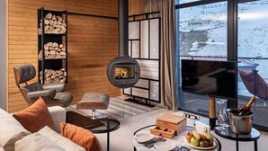 Una sala de estar acogedora con chimenea, un sofá, una mesita de centro y vistas a un paisaje nevado.