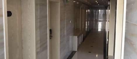 A long, narrow hallway with doors on one side and a reflective floor.