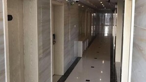 Un passadís amb parets de marbre i un sòl polit, que condueix a una habitació amb una porta.