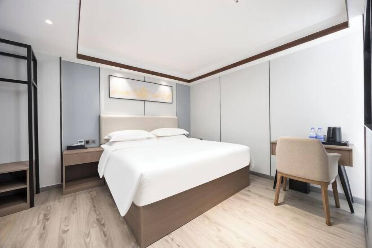 A modern hotel room with a large bed, a desk, and a chair.