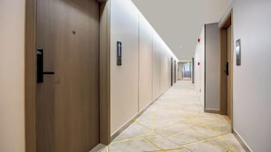 A hotel hallway with wooden doors, a patterned carpet, and a long corridor. - BONUS HOTEL (Shenzhen)