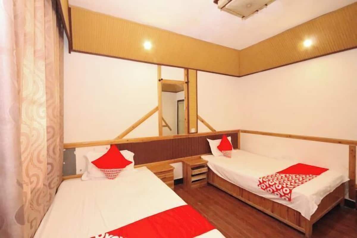 Quarto com duas camas, cabeceira de madeira, espelho e cortina estampada.