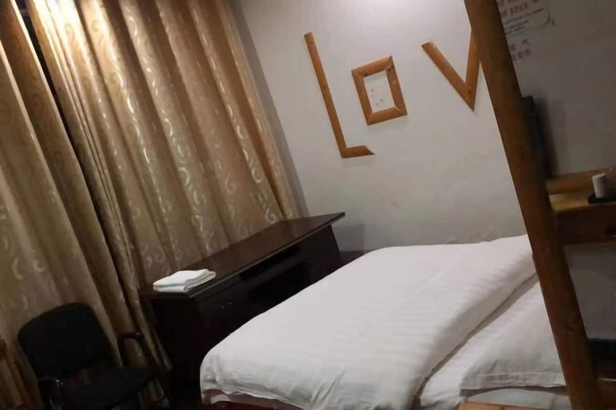 Quarto de hotel com cama, escrivaninha, cadeira e parede com um grande letreiro em formato de 'L' e 'V'.