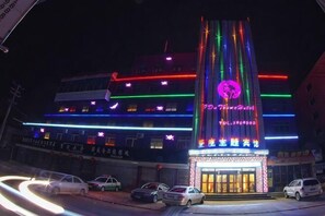 A building with a prominent vertical sign, multiple floors, and a brightly lit facade.