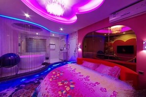 A bedroom with a bed, a mirror, and a TV.
