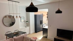 A modern living room with a sofa, dining table, TV, and kitchen in the background. - Redwing- free parking- Grade Ii listed- ground (Huntingdon)