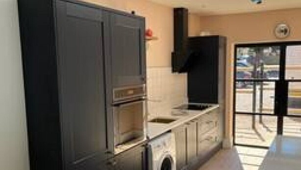 A compact kitchen with dark cabinets, a built-in oven, a washing machine, and a skylight. - Redwing- free parking- Grade Ii listed- ground (Huntingdon)