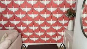 A dining area with a black table and four chairs, a red and white patterned wallpaper, and a beige sofa in the background. - Redwing- free parking- Grade Ii listed- ground (Huntingdon)