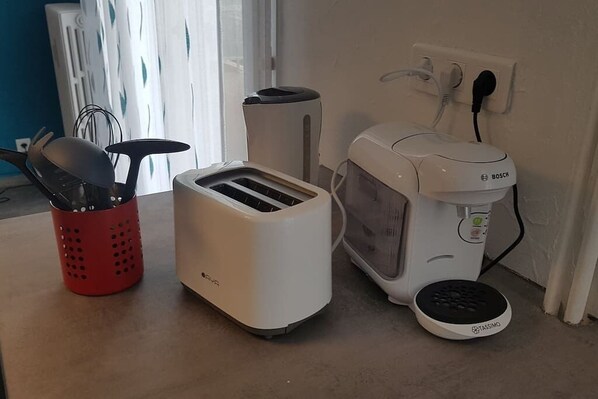 Una cocina con un tostador, una máquina para hacer pan y una cesta roja con utensilios.