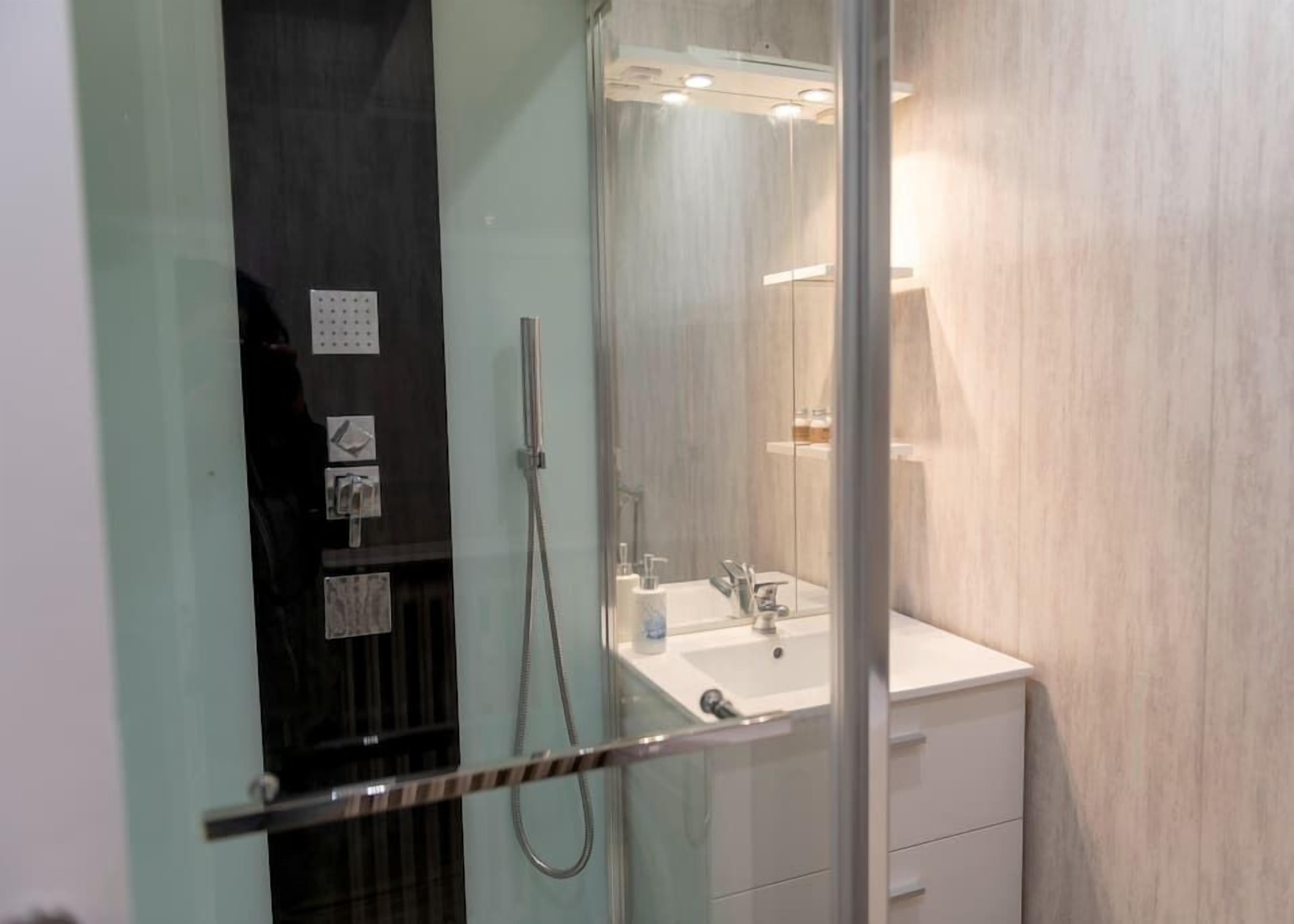 Un bagno moderno con doccia vetrata, lavandino bianco e specchio.