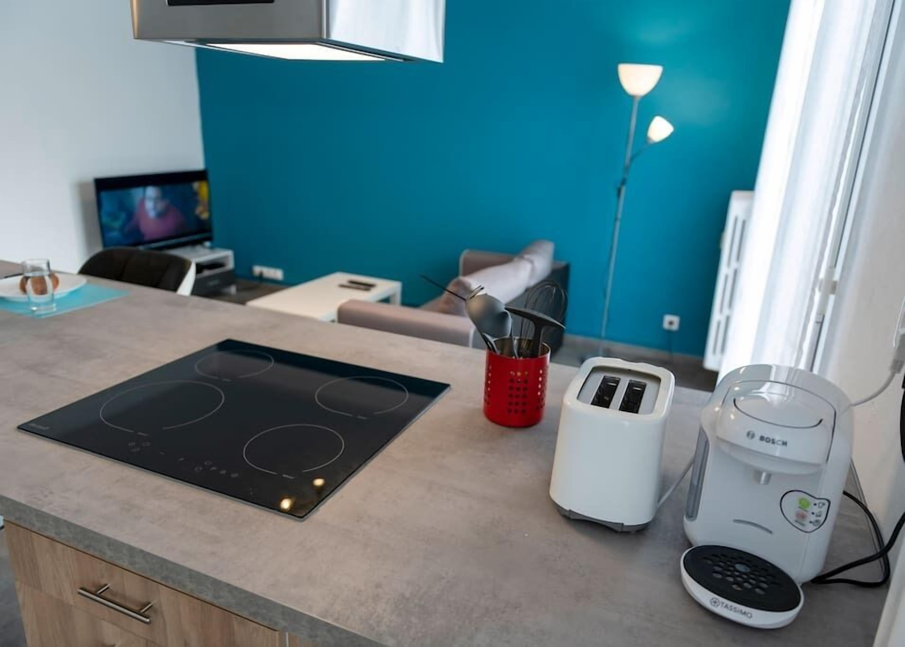 Une cuisine moderne équipée d’une plaque de cuisson à induction, d’un grille-pain et d’une machine à café.