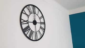 Un reloj de pared redondo con números romanos sobre una pared blanca.