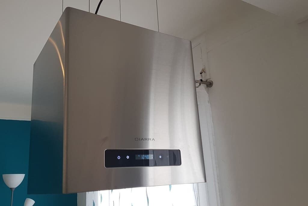 A stainless steel air conditioning unit with a digital display and control panel, mounted on a wall.