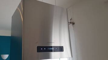 A stainless steel air conditioning unit with a digital display and control panel, mounted on a wall.