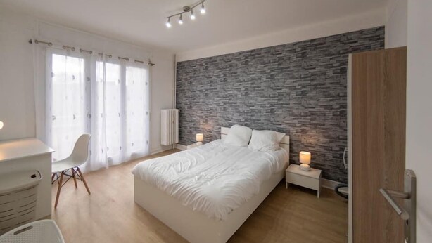 Een moderne slaapkamer met een groot bed, een bureau en een stoel.