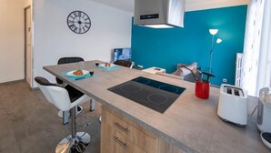 Een moderne keuken met een centraal eiland, een inbouwfornuis en een klok aan de muur.