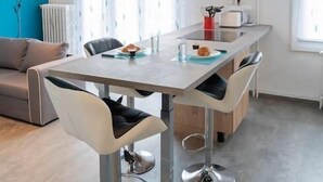 Een moderne eetruimte met een tafel, stoelen en een keukenbar.