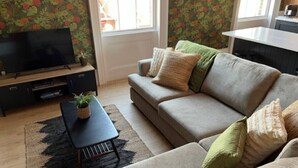 A living room with a sofa, a TV, a small table with a plant, and a patterned rug. - Field Maple -free parking -Grade Ii listed- first (Huntingdon)