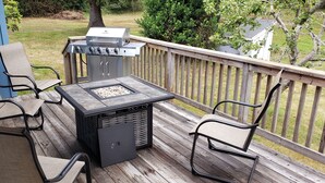 Eine Terrasse mit Grill, Stühlen und einem Tisch.