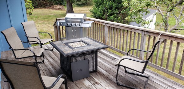 A deck with a grill, chairs, and a table.
