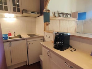 Uma cozinha compacta com pia, uma cafeteira Bosch e um refrigerador pequeno.