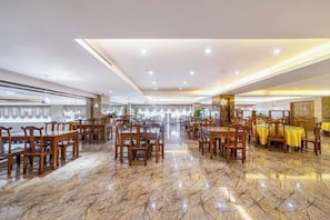 A spacious dining area with multiple tables and chairs, a polished marble floor, and a high ceiling with recessed lighting. - Feng Ya Hotel (Jinjiang)